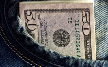 Lembaran uang kertas dollar Amerika Serikat dildetakkan pada saku celana jins.